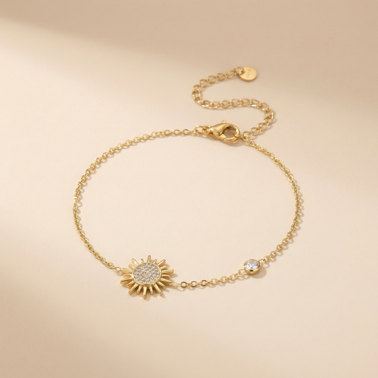 Gold bracelet with sunflower charm on a beige background