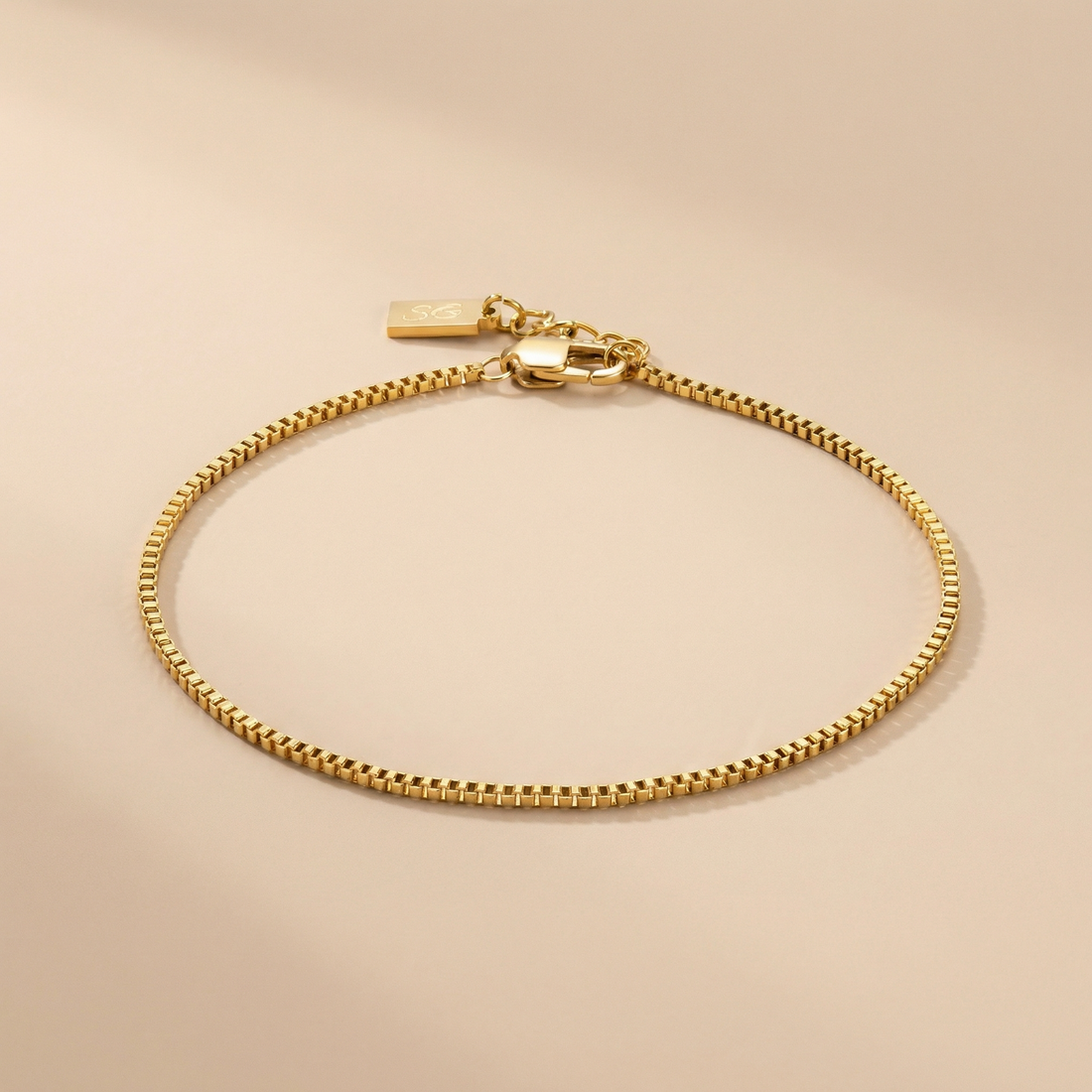 Gold linea box bracelet on a beige background