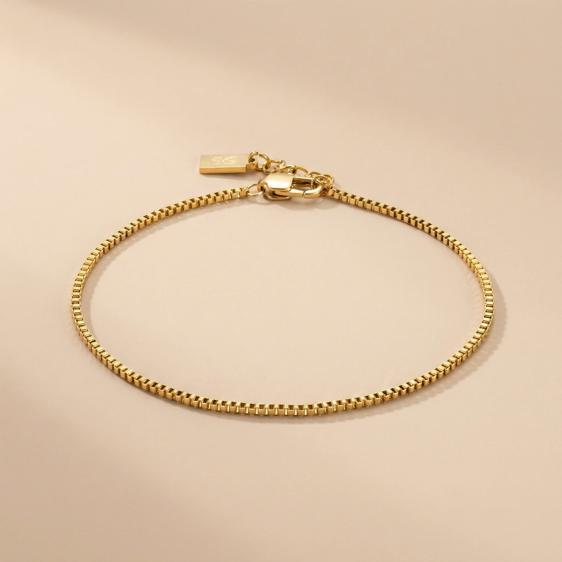 Gold linea box bracelet on a beige background
