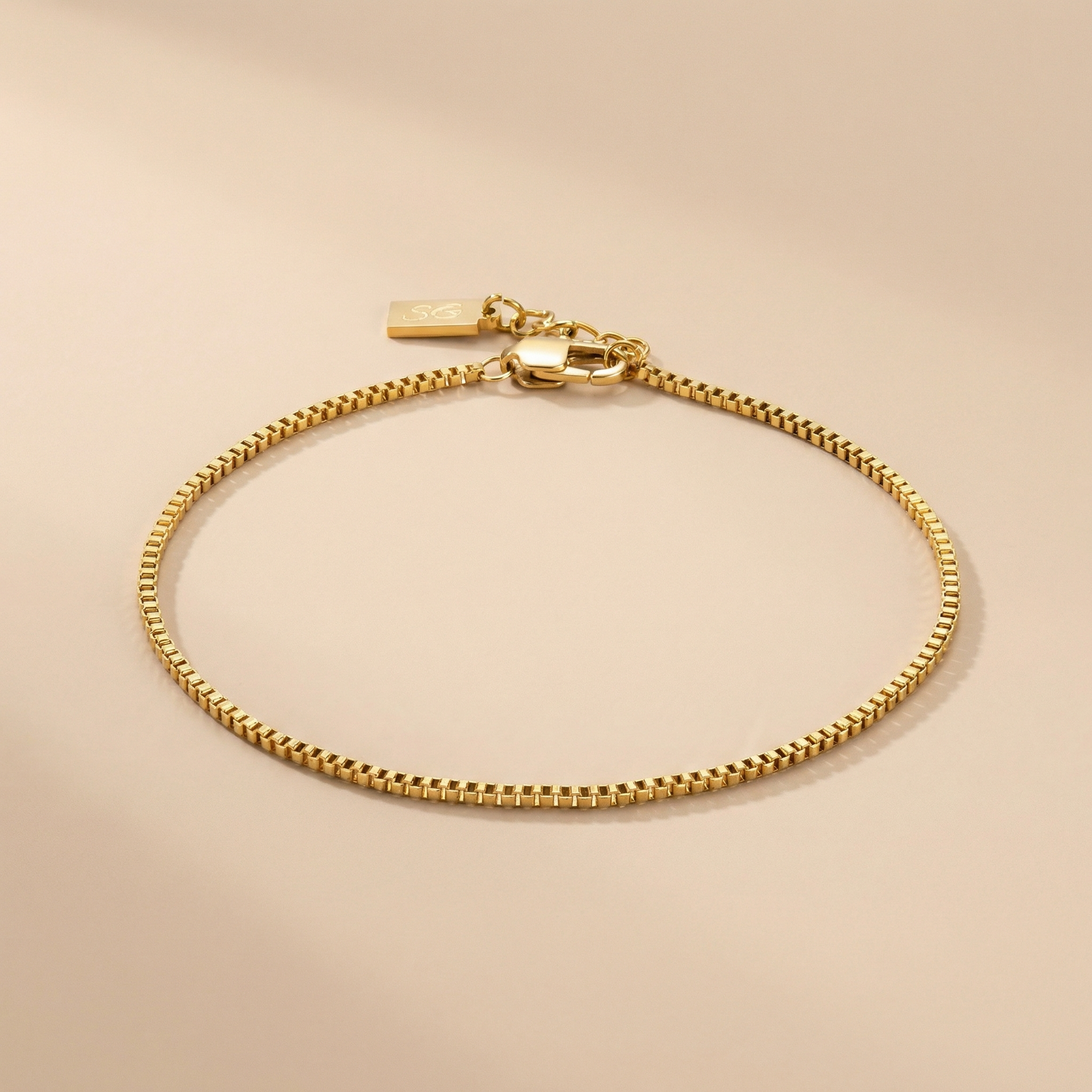 Gold linea box bracelet on a beige background
