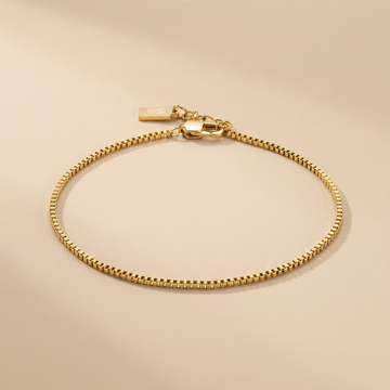 Gold linea box bracelet on a beige background