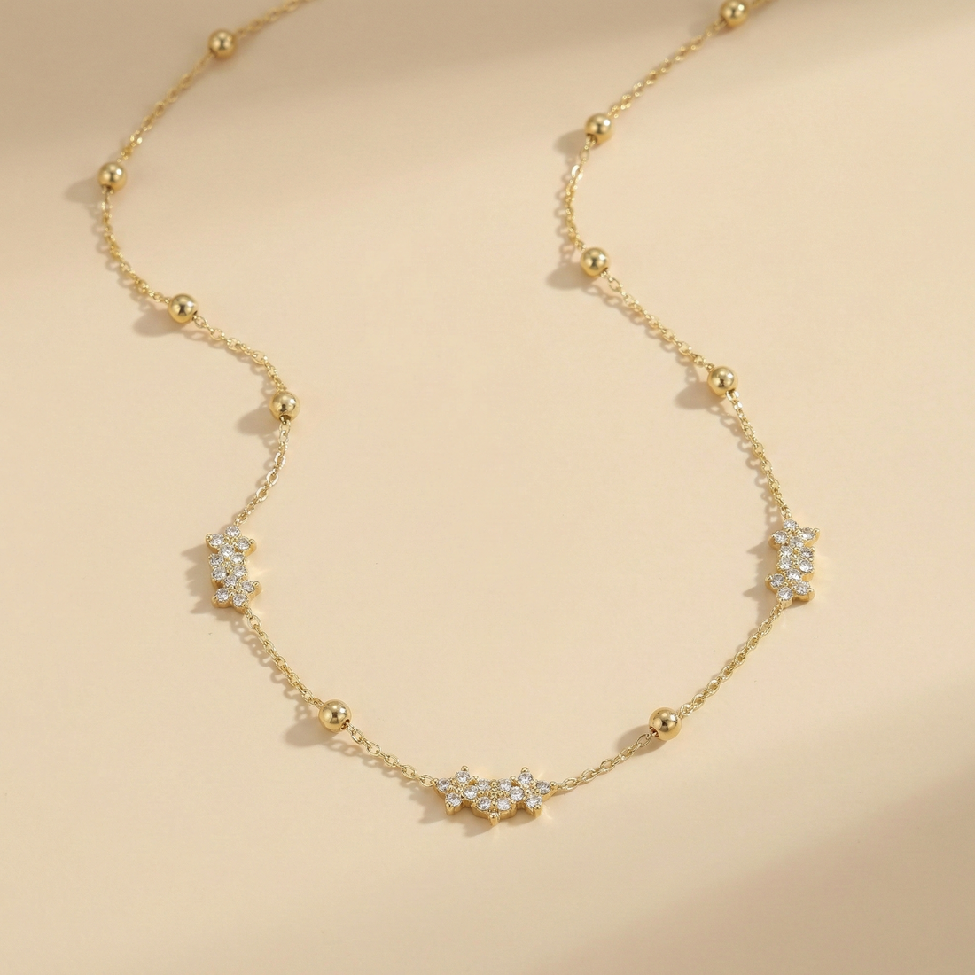 Gold necklace with diamond accents on a beige background