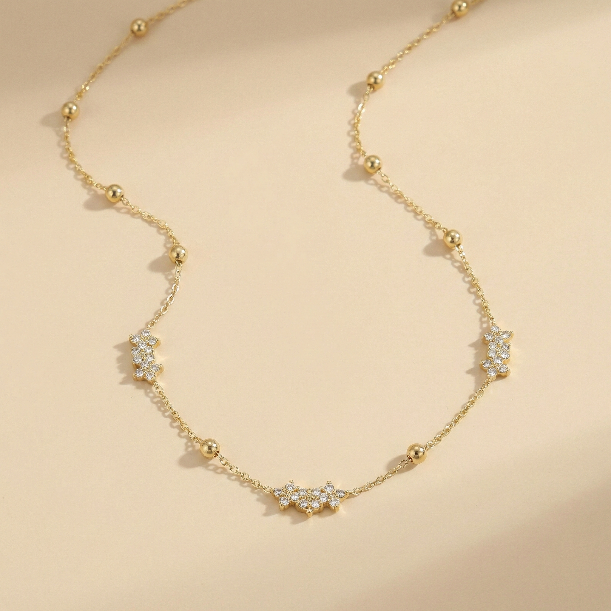 Gold necklace with diamond accents on a beige background