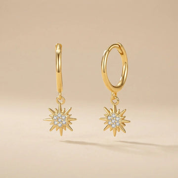 Gold hoop earrings with star-shaped pendants on a beige background