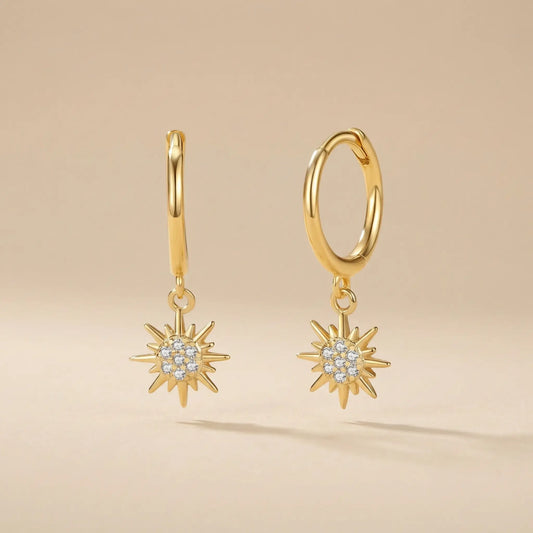 Gold hoop earrings with star-shaped pendants on a beige background