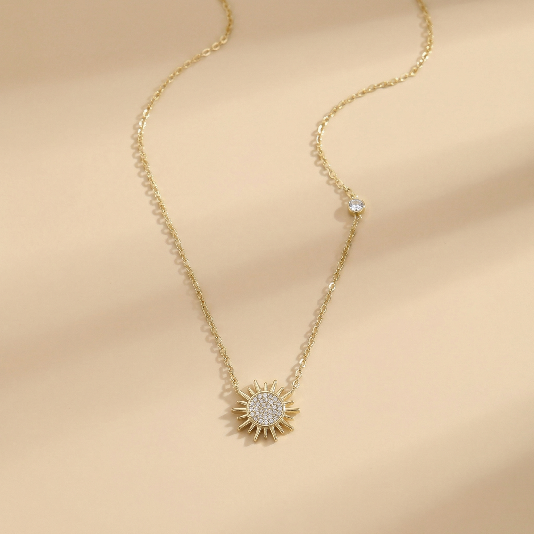 Gold necklace with a sunflower pendant on a beige background
