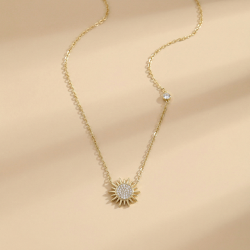 Gold necklace with a sunflower pendant on a beige background
