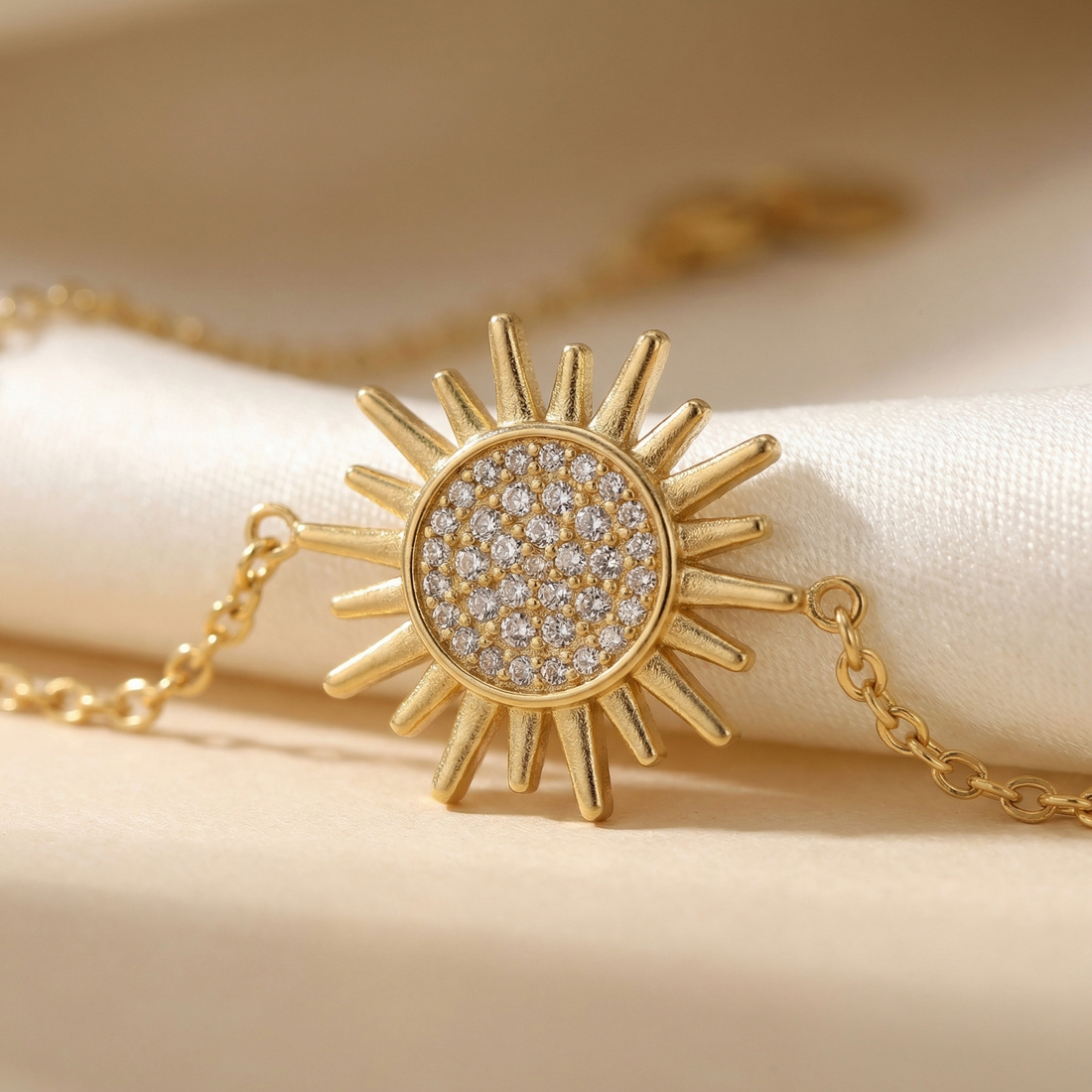 Gold bracelet with sunflower charm on a beige background