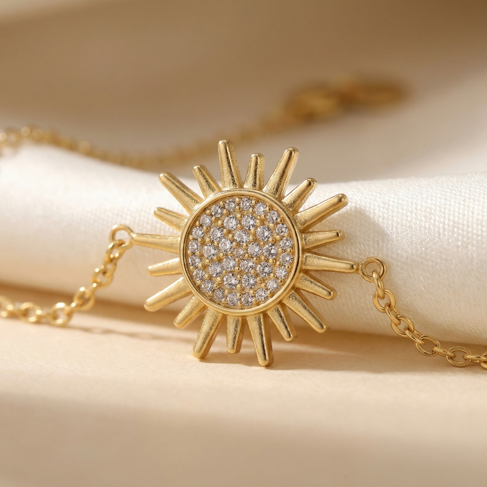 Gold sun-shaped necklace with diamond-like stones on a beige background