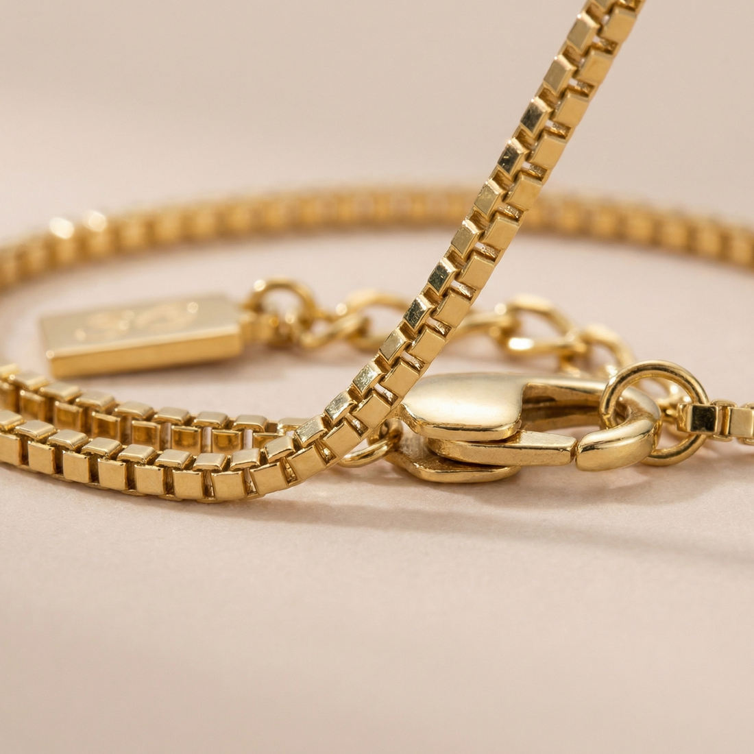 Gold linea box bracelet on a beige background