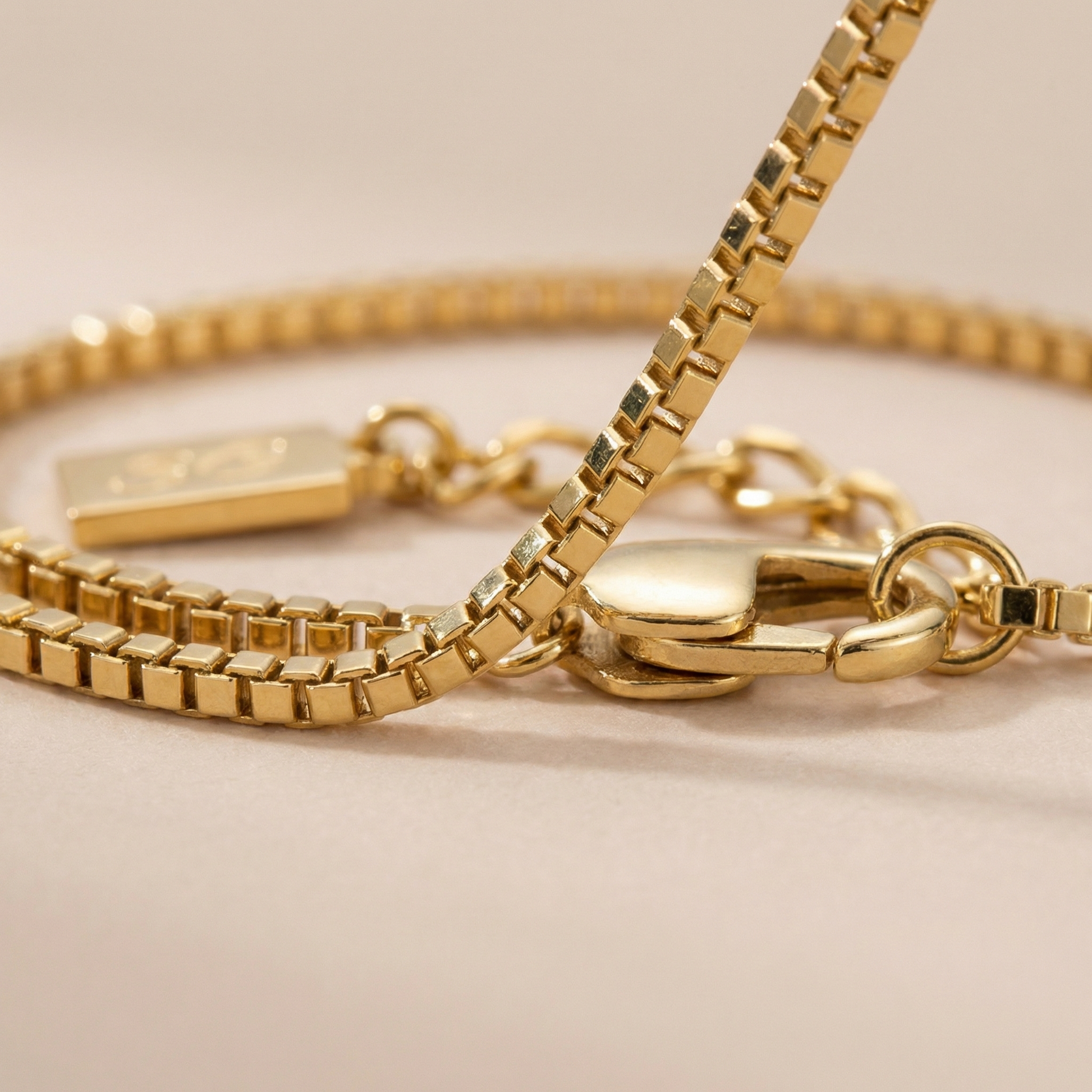 Close-up of a gold box bracelet on a beige background