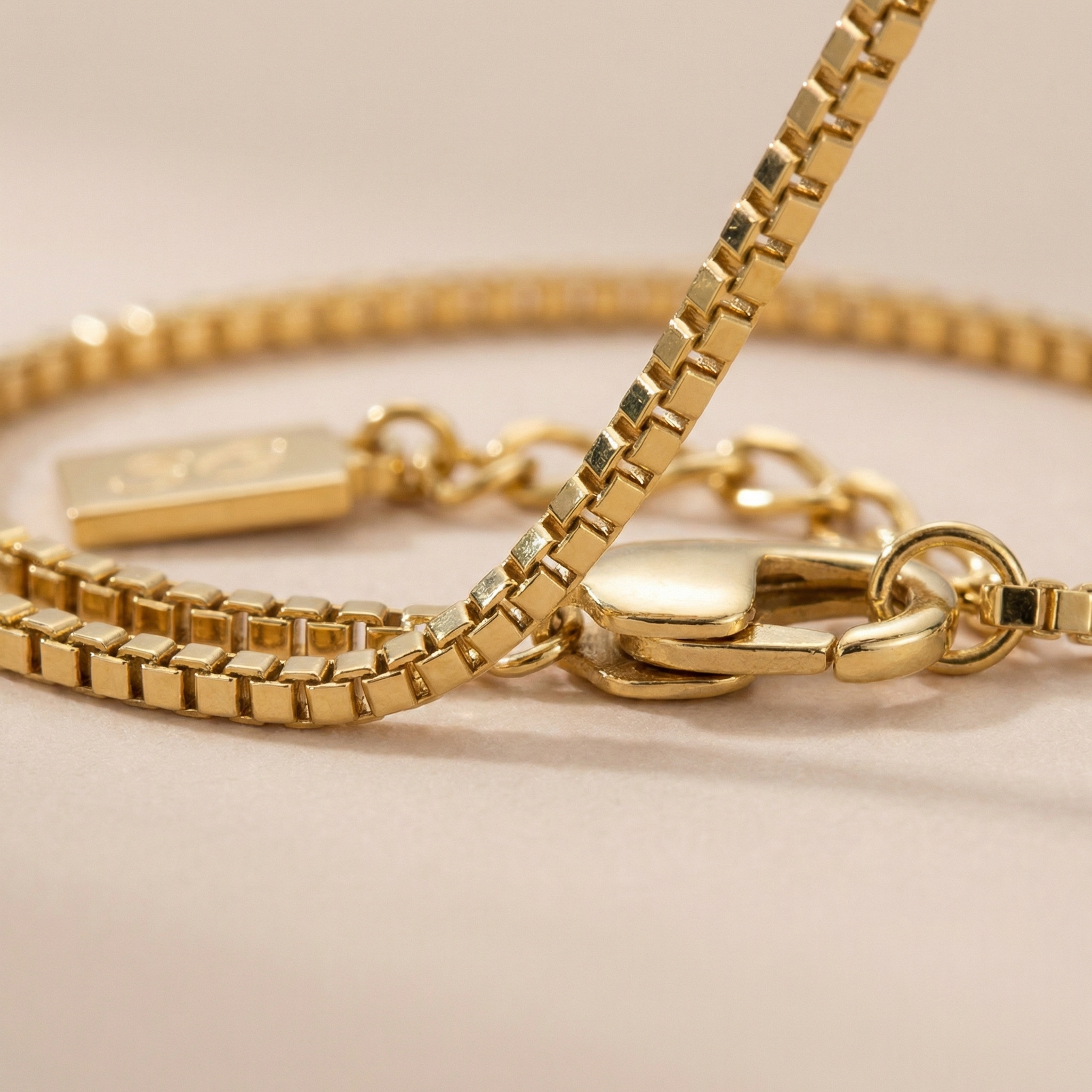 Close-up of a gold box bracelet on a beige background