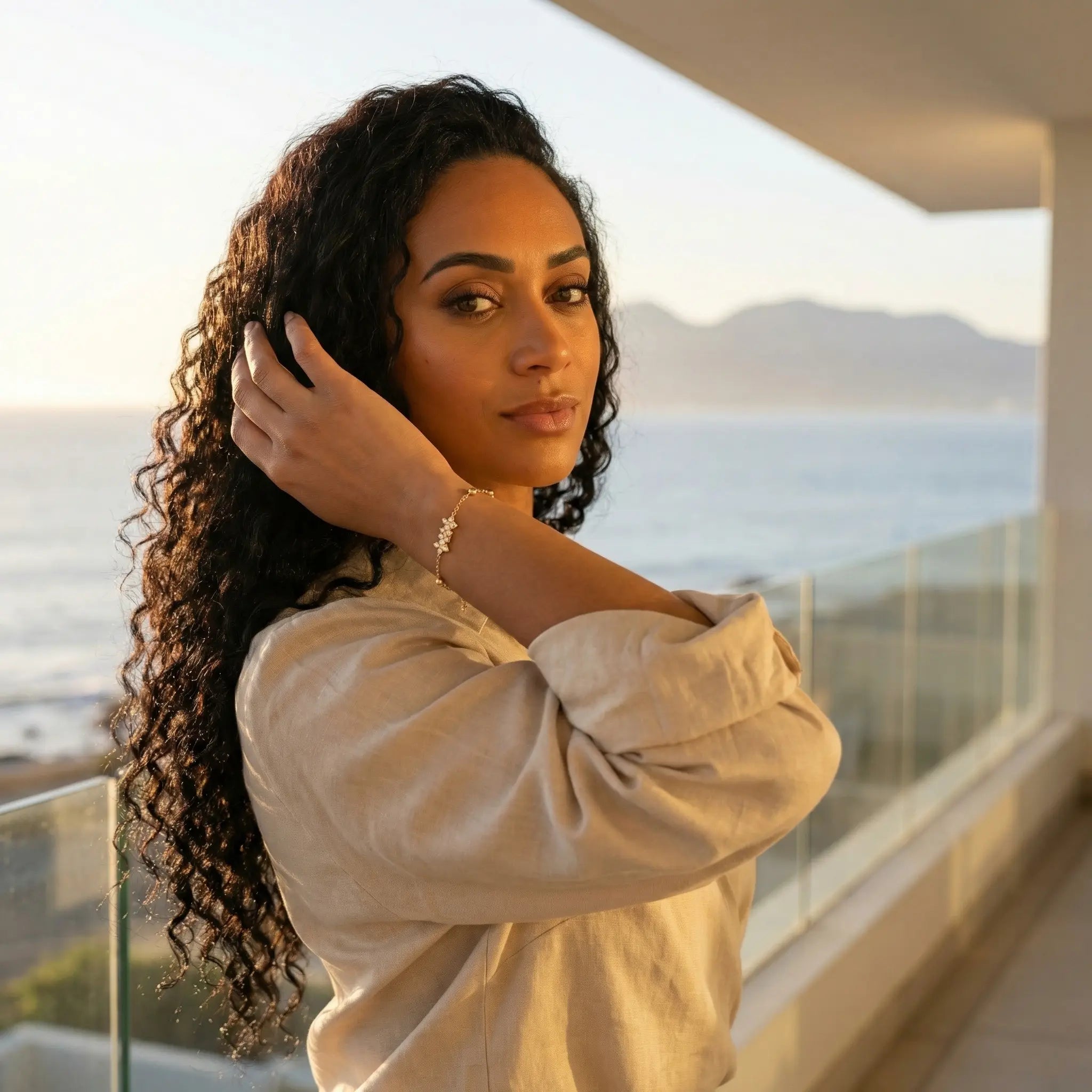 Woman standing on a balcony wearing a vela bracelet with a scenic view of mountains and ocean in South-Africa