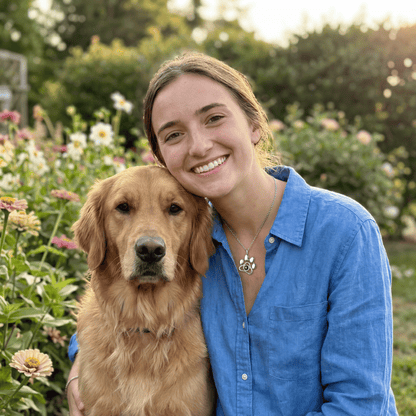 Woman in a blue shirt with a golden retriever in a garden