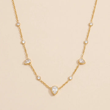 Gold necklace with teardrop-shaped gemstones on a beige background