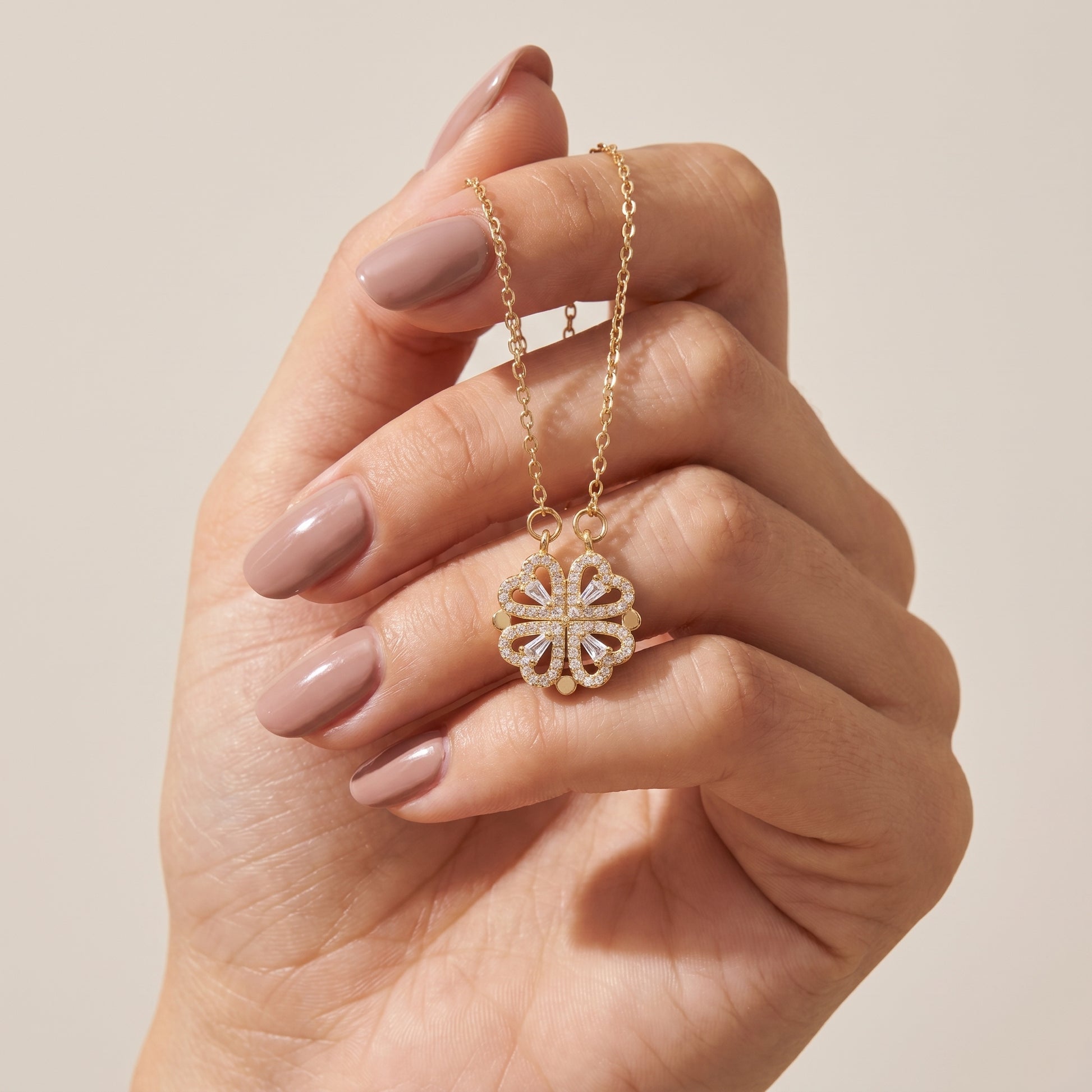Hand holding the gold clover heart pendant showing the cubic zirconia detail