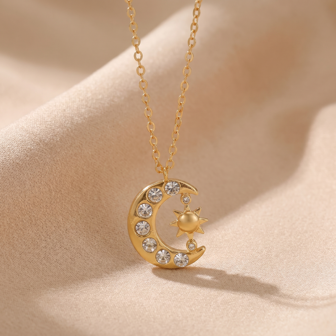 Gold sun and crescent moon zircon necklace on a soft beige background