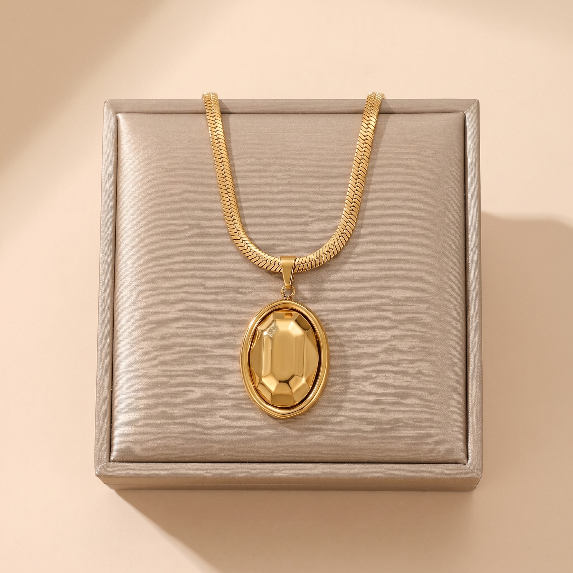 Gold chunky oval link pendant necklace on a soft beige background