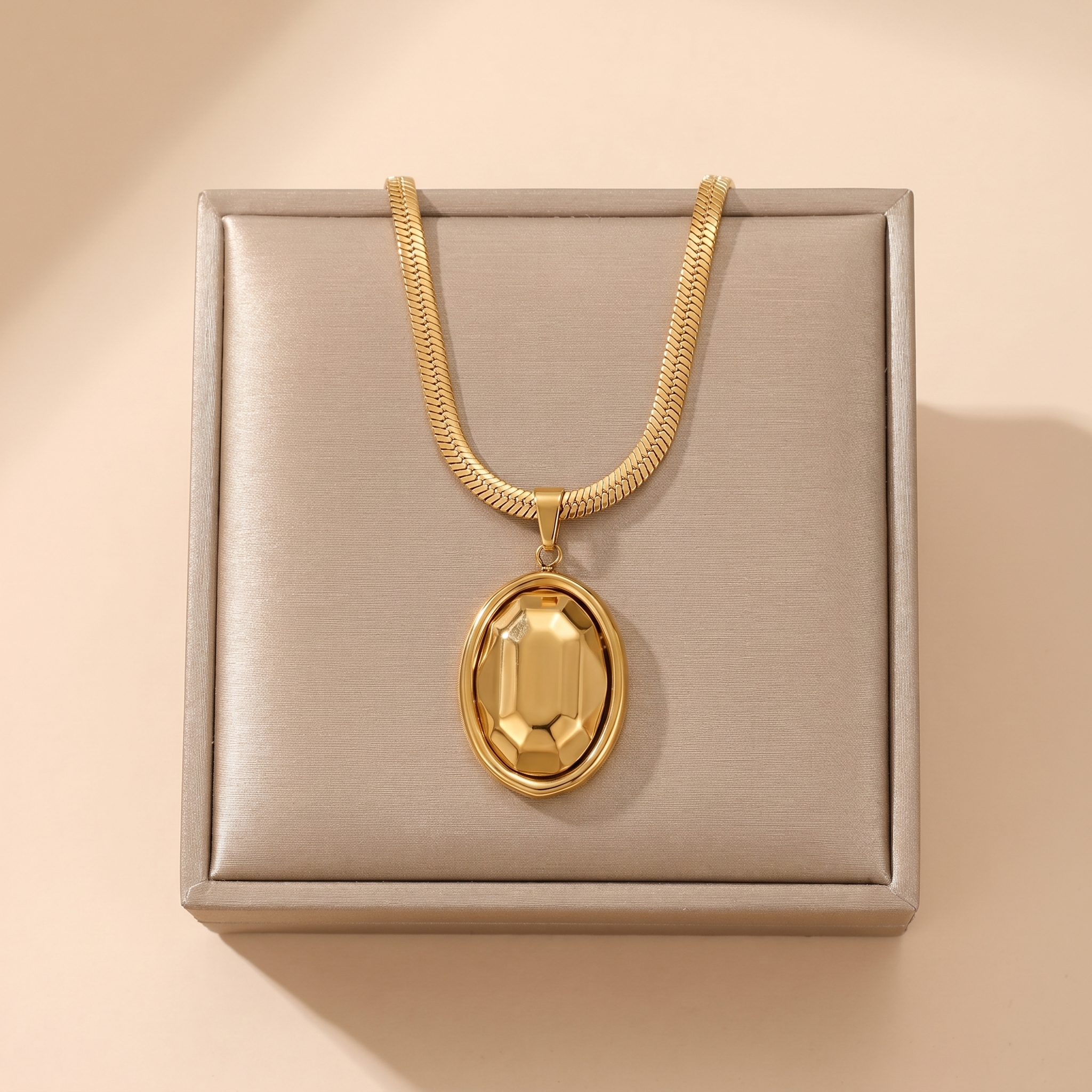Gold chunky oval link pendant necklace on a soft beige background