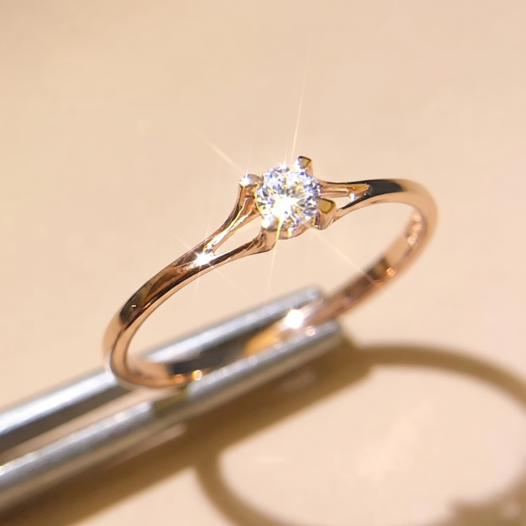 Minimalist 4mm cubic zirconia solitaire ring on a soft beige background