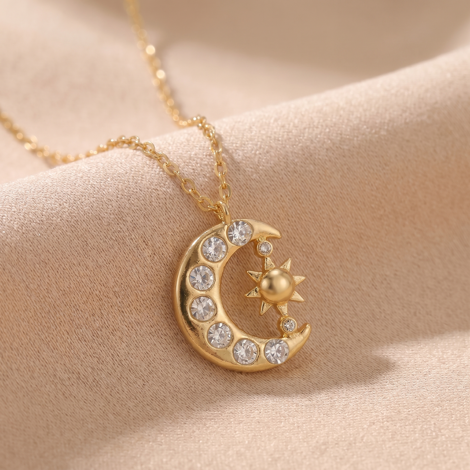 Macro detail of the gold sun and crescent moon pendant on beige
