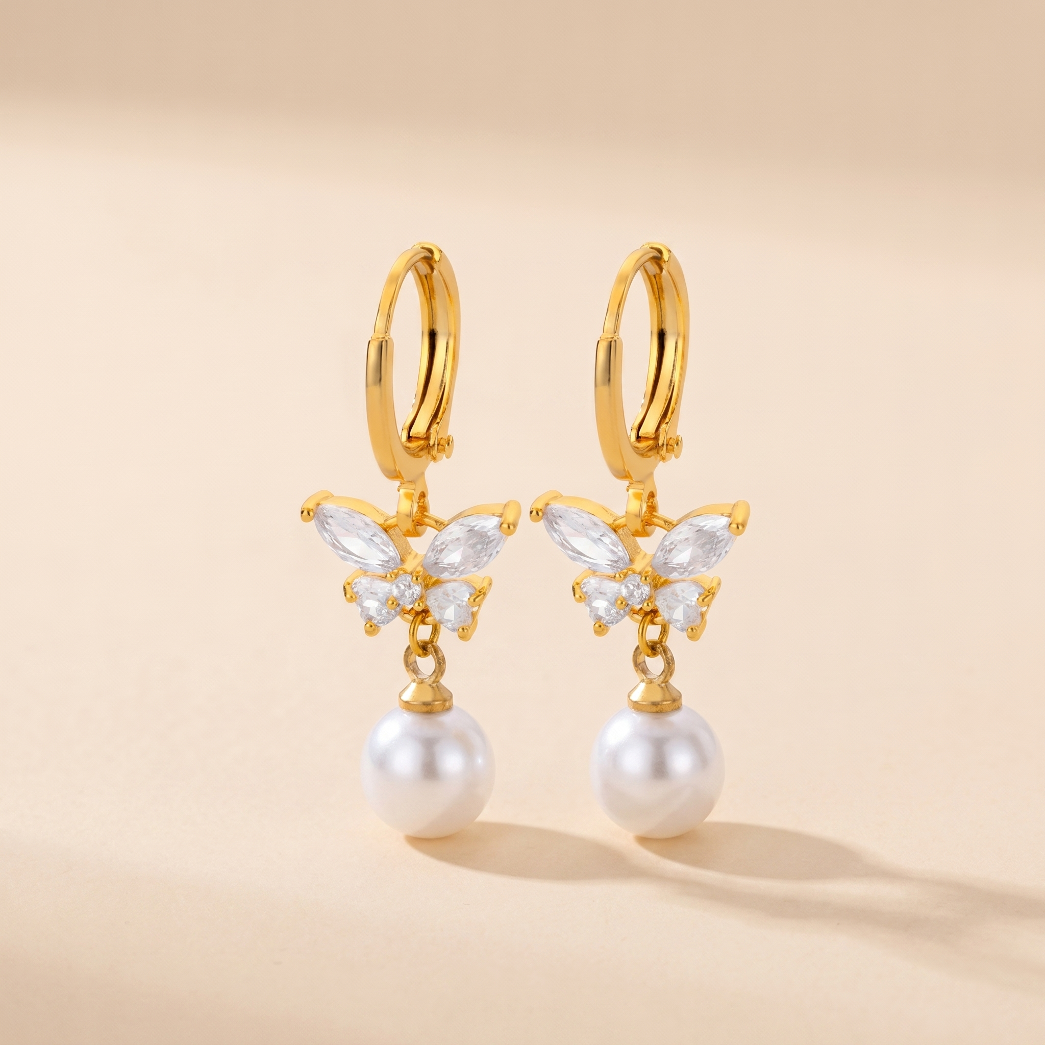 Butterfly Pearl Drop Earrings on soft beige background