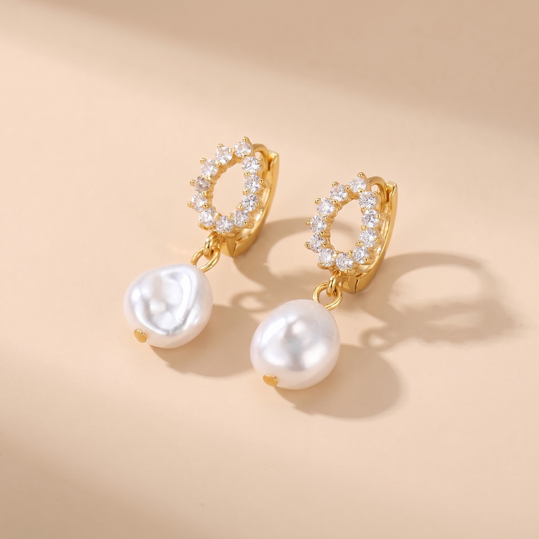 Pave Pearl Drop Huggie Earrings on soft beige background
