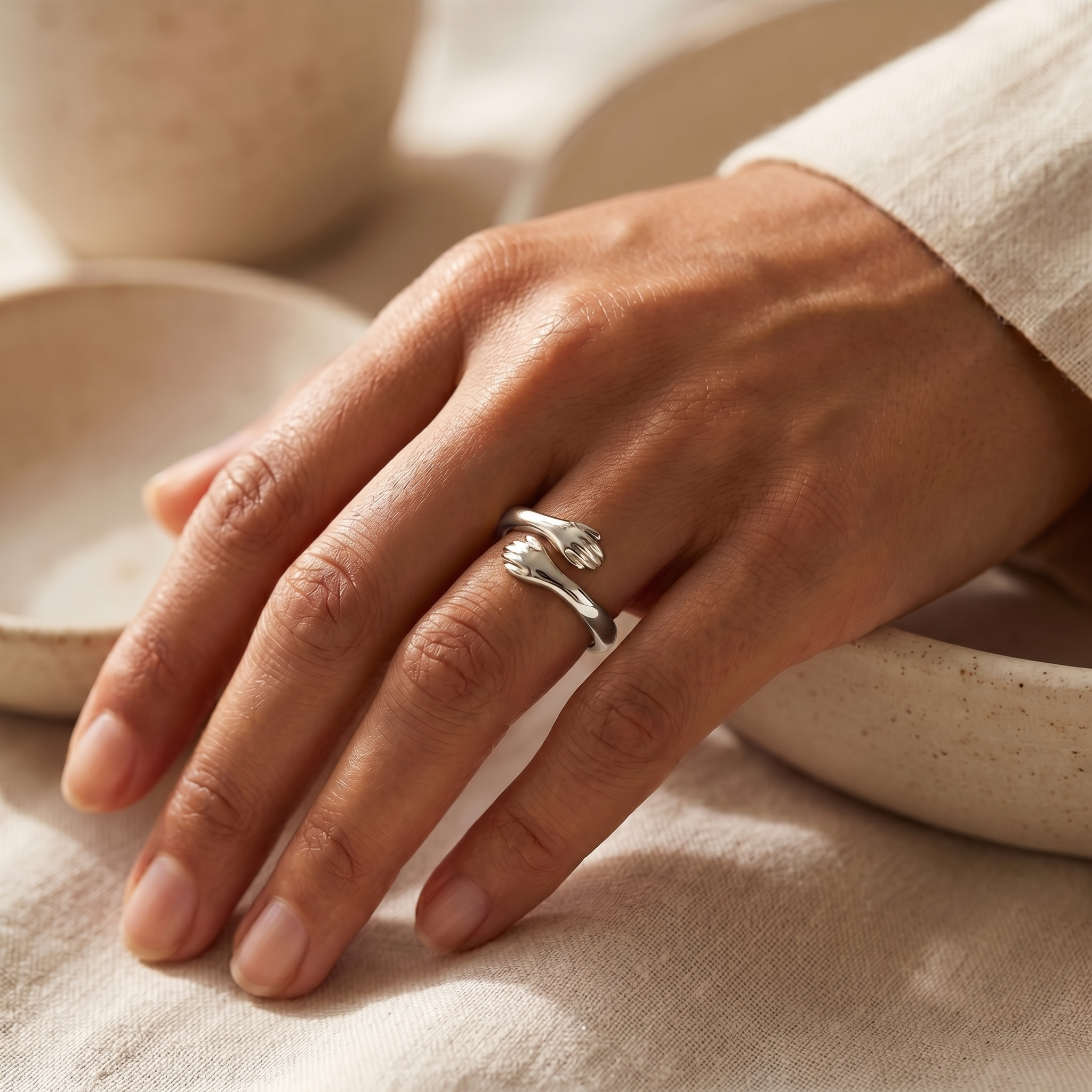 Silver hug ring worn on hand, warm beige lifestyle