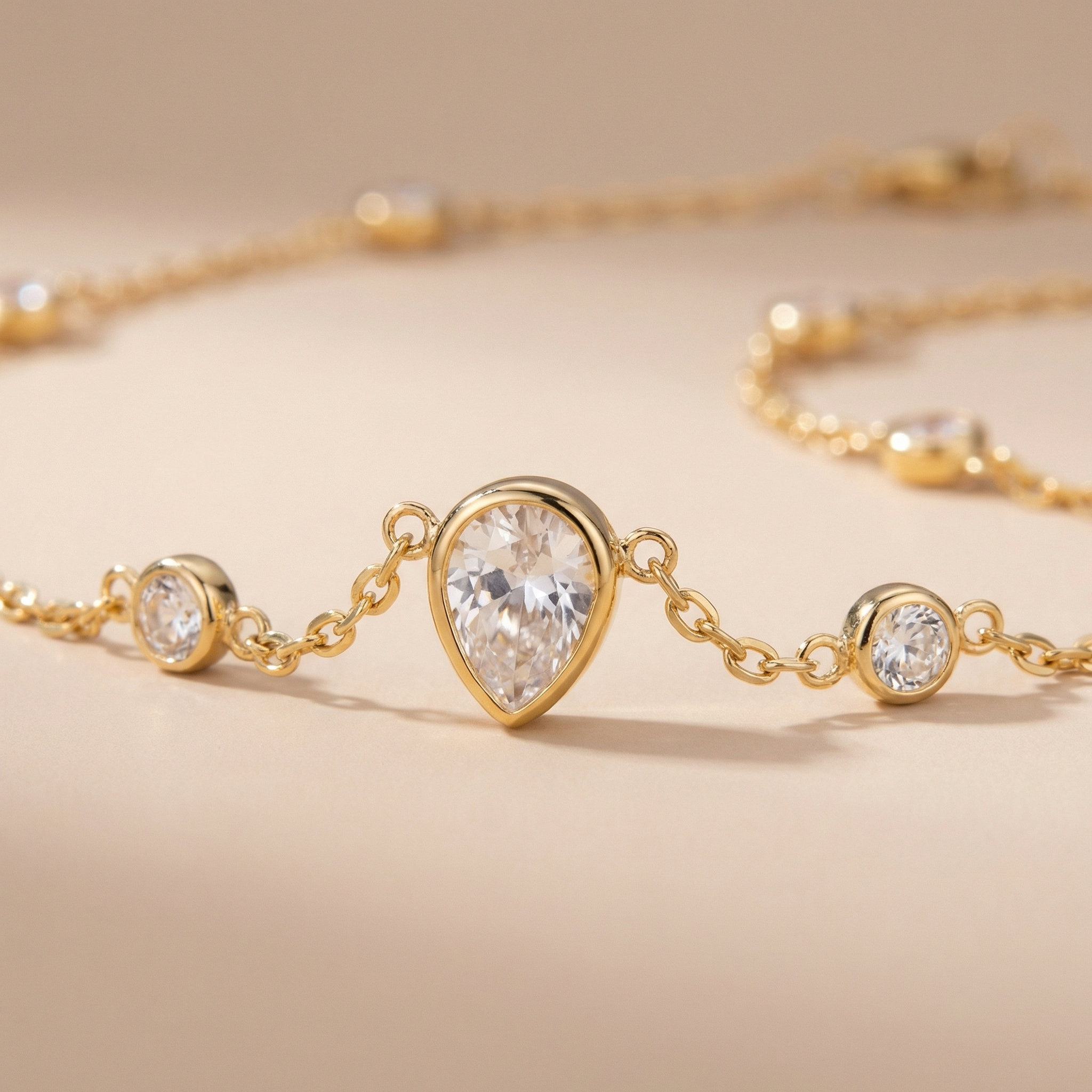 Gold bracelet with tear-shaped diamond on a beige background