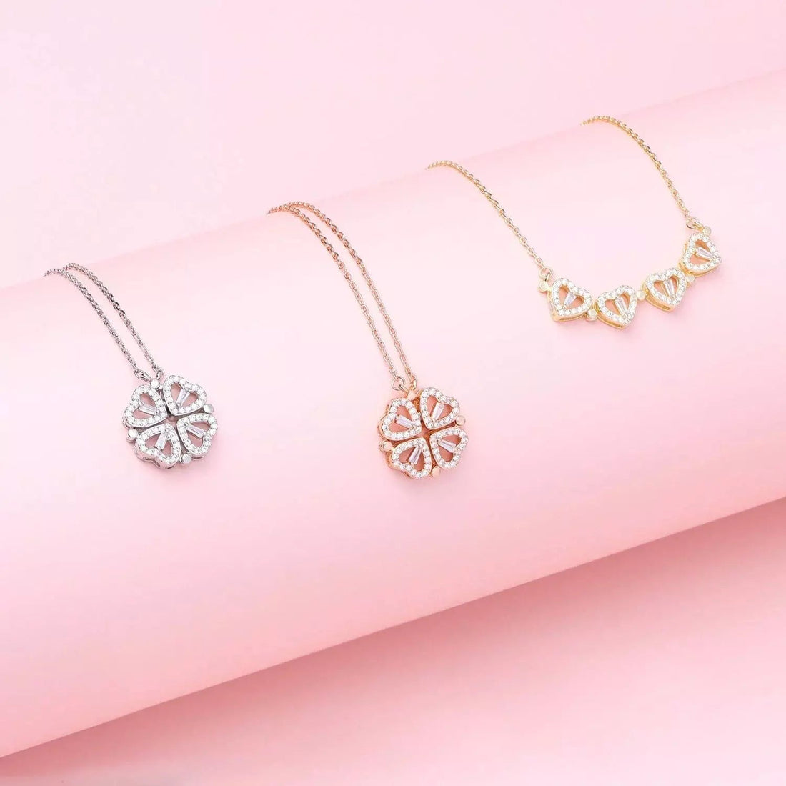 Three necklaces with heart-shaped pendants on a pink background
